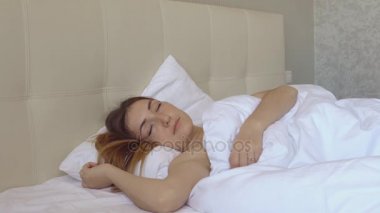 güzel kız büyük yatağında uyanır ve pencereden görünüyor.