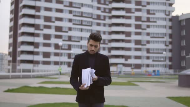 Attrayant jeune homme d'affaires en costume noir jeter des documents en plein air — Video
