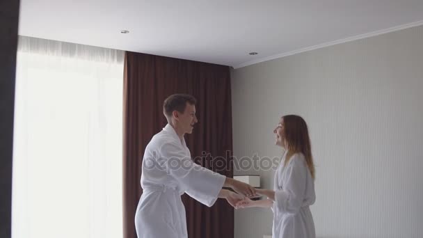 Jovem casal saltar para cima e para baixo em uma cama de hotel . — Vídeo de Stock
