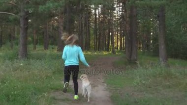 Genç kadın ile köpek ormanda yürüyor