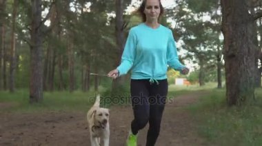 Genç kadın ile köpek ormanda yürüyor
