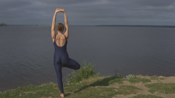 Йога жінка в спортивному одязі позувати проти озеро — стокове відео