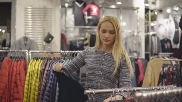 Hermosa mujer revisando su ropa nueva en la boutique — Vídeos de Stock