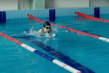 genç kadın gözlük ve kap mavi su kapalı yarış havuzda kurbağalama kontur stili