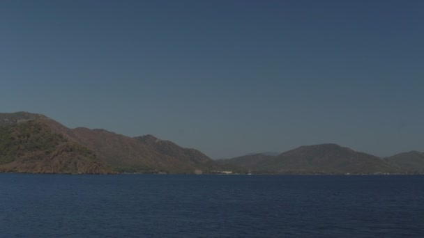 Barcos grandes y pequeños navegan a través del tranquilo mar entre las verdes colinas en un cálido y soleado día de verano. — Vídeo de stock