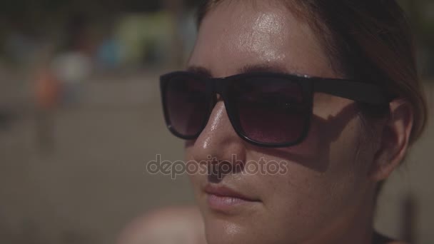 Close up van een jonge vrouw in zonnebril zonnebaden op het strand in de zomer. — Stockvideo