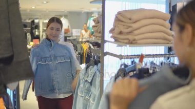 Güzel kız çalışırken giysi moda mağaza alışveriş yaparken yansıması Aynaya bakar