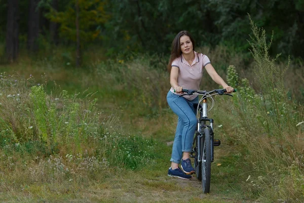Молодая красивая женщина, катающаяся на велосипеде в лесу. Прогулка на велосипеде в парке, активный здоровый образ жизни — стоковое фото
