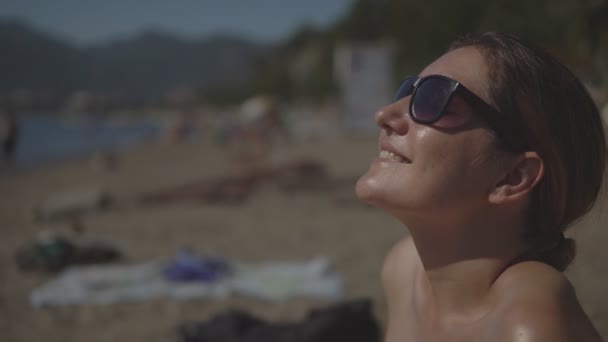 Jeune femme en lunettes de soleil se détendre et bronzer sur la plage en été — Video