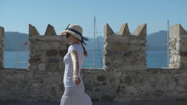 Jeune jolie fille dans le chapeau tourne et tourbillonne sur la forteresse de pierre le jour ensoleillé d'été — Video