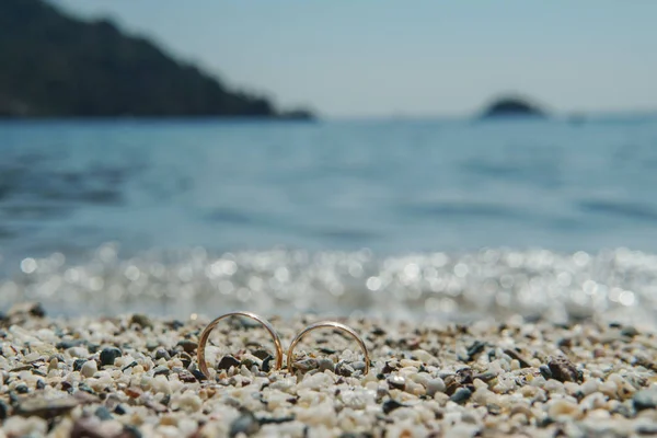 背景の青い海のビーチで結婚指輪, — ストック写真