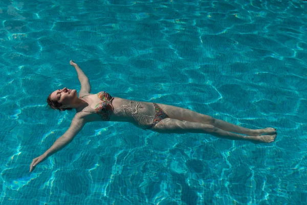 Молода жінка в купальнику плаває в басейні — стокове фото