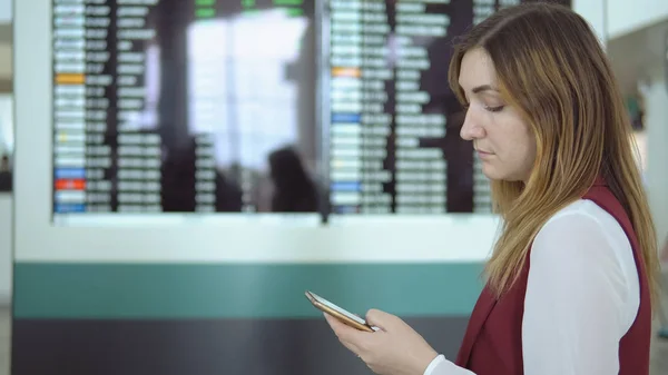 Traurige Frau tippt Smartphone am Flughafen ein — Stockfoto