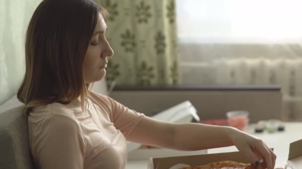 Ensam ledsen flicka med pizza sitter på soffan hemma och klockor en film — Stockvideo