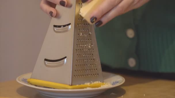 Дівчина нарізає сир на металевій тертці на тарілці — стокове відео