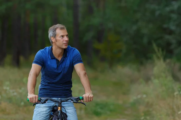 Человек ездит на велосипеде в сосновом лесу, спортивный отдых — стоковое фото