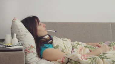 Hasta bir kadın vücut ısısı bir termometre ile ölçer.