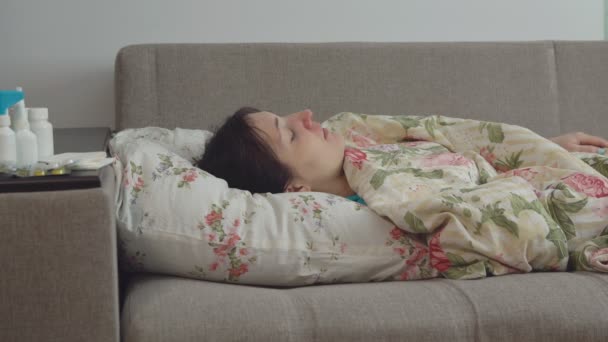 Mladá žena leží na posteli s kašlem — Stock video