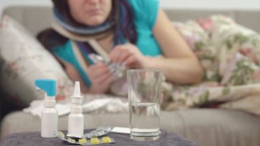 tabletler, sprey ve sandalye ve genç hasta kadın su arka planda yatakta bir hap alır.