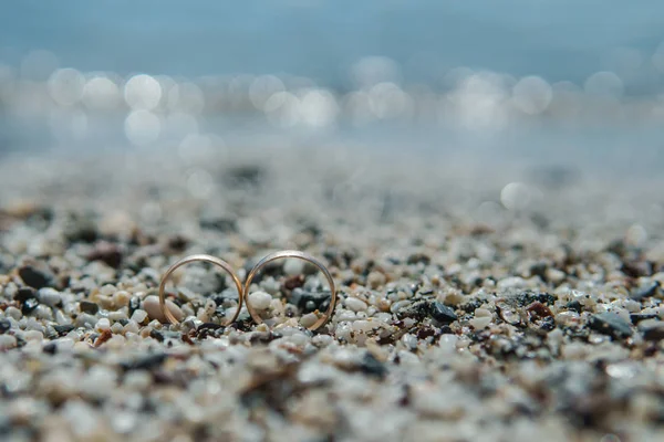 Alianças de casamento na areia do seixo na praia — Fotografia de Stock