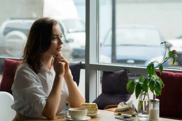 Hübsche Mädchen genießt einen duftenden Kaffee und süßen Kuchen sitzen im Kaffeehaus. Geschäftsfrau rastet in der Pause aus — Stockfoto