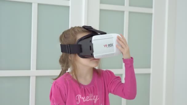 Kleines Mädchen im rosa Kleid spielt mit virtueller Brille. Kleingedrucktes — Stockvideo