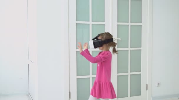 Маленькая девочка в розовом платье играет в виртуальных очках — стоковое видео