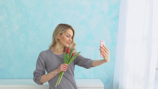 Mooie jongedame met een boeket van tulpen is het fotograferen van zichzelf op de telefoon — Stockvideo