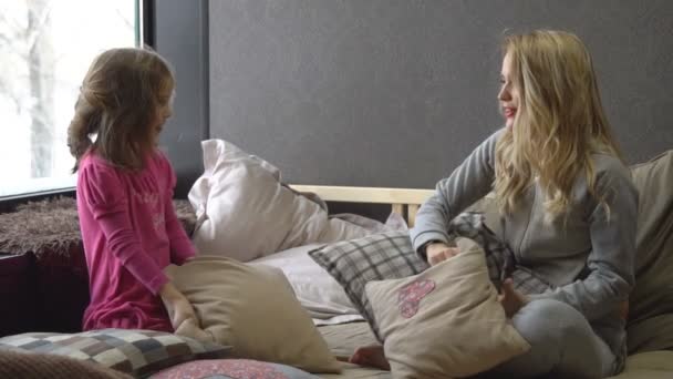 Moeder en dochter spelen met kussens op het bed — Stockvideo