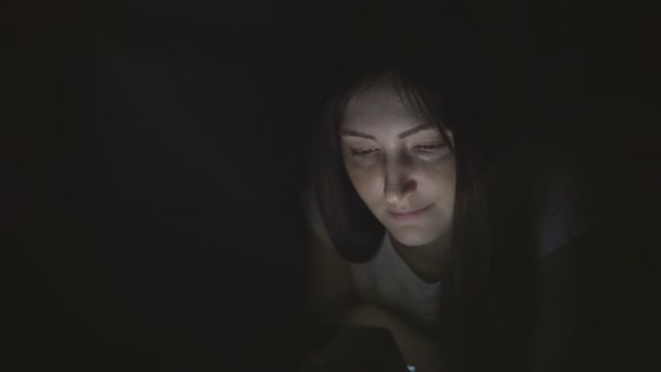 Mooie vrouw in het donker bij nacht zit met een telefoon in sociale netwerken — Stockvideo