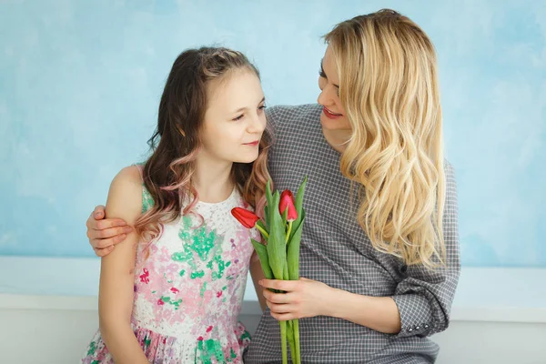 Мать и дочь с букетом тюльпанов на фоне синей стены — стоковое фото