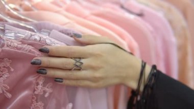 yavaş çekimde kadının el giysiler içinde bir butik tarama, bir raf rastlamak.