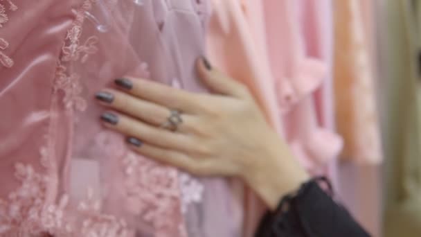 Женские руки бегают по вешалке с одеждой, просматривая бутик . — стоковое видео