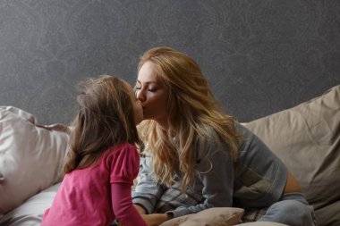 Anne ve küçük kızı yatağa oturmuş ve şapır şupur