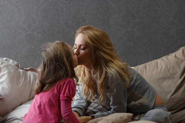 Мать и маленькая дочь сидят на кровати и шлепают — стоковое фото