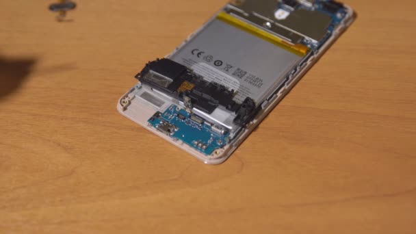 Herstellen van een mobiele telefoon op een bruin tafel. Close-up van de handen van een man — Stockvideo