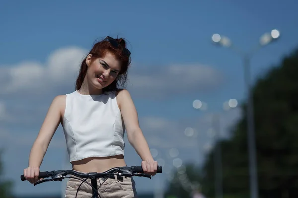 Menina bonita em shorts e tops posando de pé com bicicleta — Fotografia de Stock