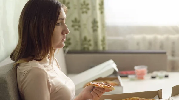 Solitaria chica triste con pizza sentado en el sofá en casa y mira una película —  Fotos de Stock