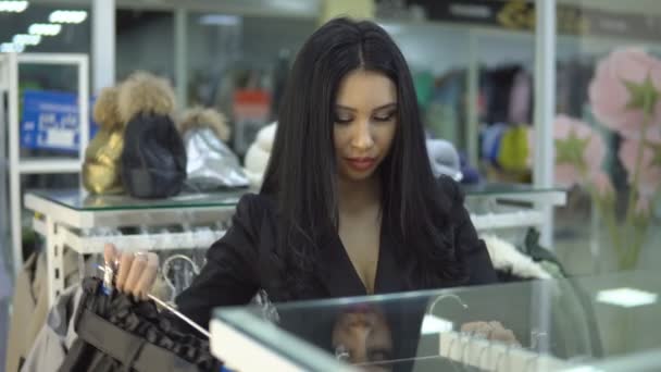 Compras en una tienda de ropa - una mujer joven actualiza su armario . — Vídeos de Stock