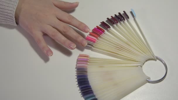 Hände eines Mädchens in einem Schönheitssalon wählt die zukünftige Maniküre in einer Farbpalette. — Stockvideo