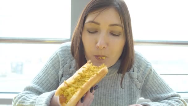 Kobieta zjada hot doga w kawiarni fast food. — Wideo stockowe