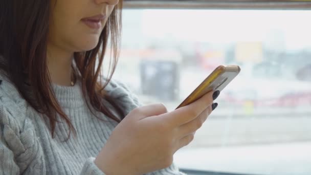 Detailní záběr mladá bruneta žena s telefonem na pozadí velké okna. — Stock video