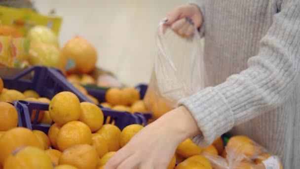 Mujer joven en el departamento de verduras del supermercado marca una bolsa de mandarinas — Vídeos de Stock