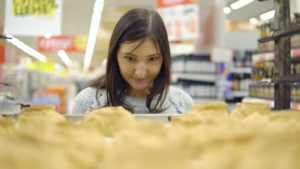 Брюнетка в хлебопекарном отделе магазина выбирает свежие пироги — стоковое видео