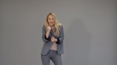 Mutlu iş dansçı kız başarılı bir anlaşma işaretleme ve freestyle ofiste gri arka plan üzerinde dans elbiseli.