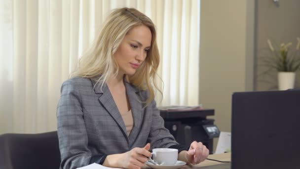 Hermosa mujer de negocios en traje trabaja con café taza en el lugar de trabajo . — Vídeos de Stock