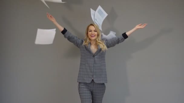 Feliz empresaria lanza páginas de documentos en papel sobre el fondo gris . — Vídeos de Stock
