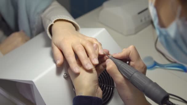 Nail-master en el salón de belleza hace una manicura para una mujer joven — Vídeos de Stock