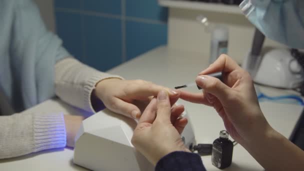 在美容院的一个年轻女子指甲上涂抹凝胶清漆的特写 — 图库视频影像
