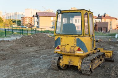 yeni özel evler arka plan üzerinde arkadan görünüşü küçük sarı buldozer,